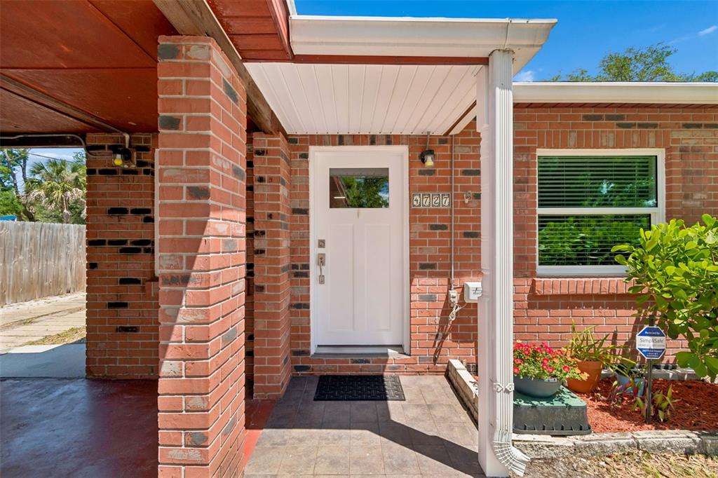 A brick exterior home features a white front door, a covered porch, and a window — 4727 W ANITA BOULEVARD, TAMPA, FL