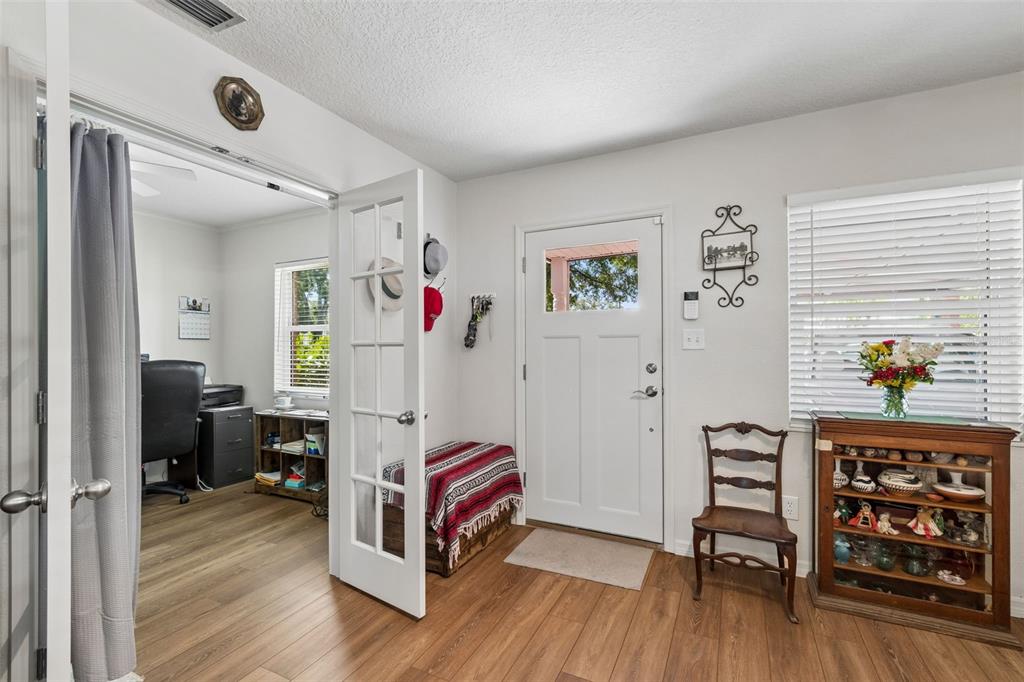 An entryway with wood-look flooring, a white front door, a glass-paneled door, and a display cabinet — 4727 W ANITA BOULEVARD, TAMPA, FL