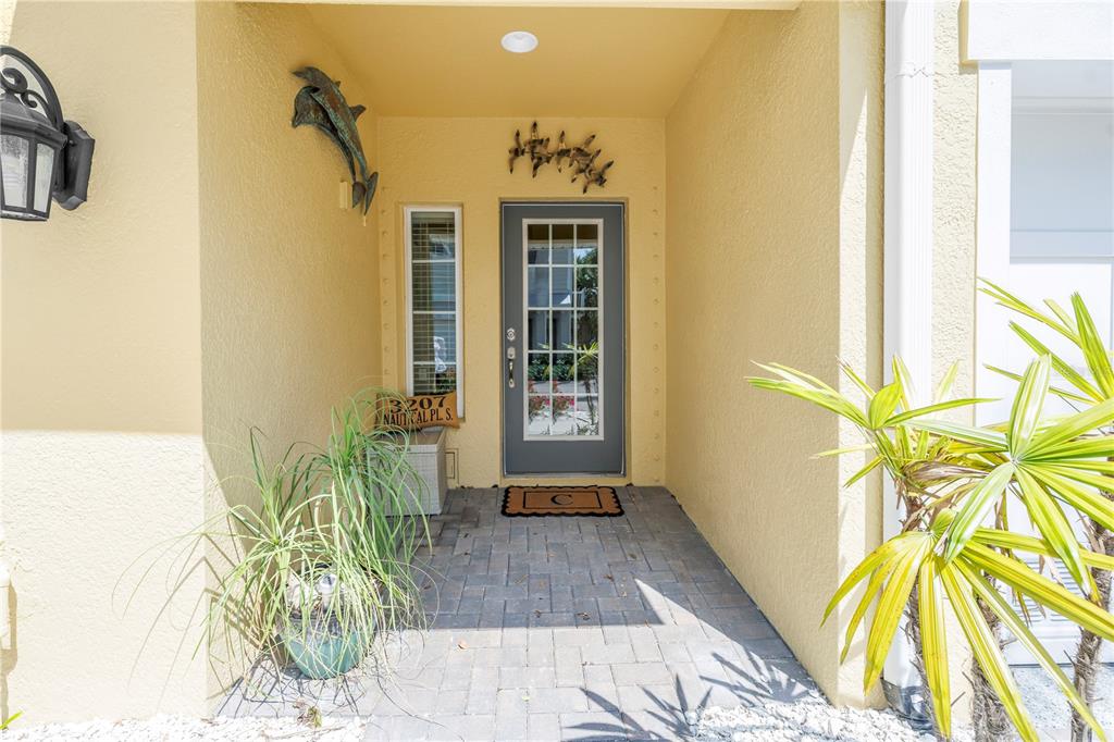 A front entryway features a gray door, a side window, and a dolphin wall sculpture — 3207 NAUTICAL PLACE S, ST PETERSBURG, FL
