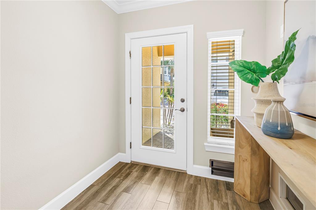 An entryway features wood-look flooring, a white front door with glass panes, and a console table — 3207 NAUTICAL PLACE S, ST PETERSBURG, FL