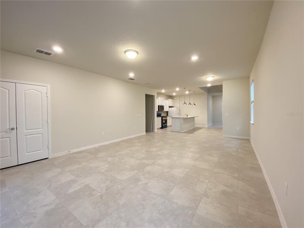 An open-concept living area features light-colored tile flooring and a kitchen with a central island — 7360 OAKMOSS LOOP, DAVENPORT, FL