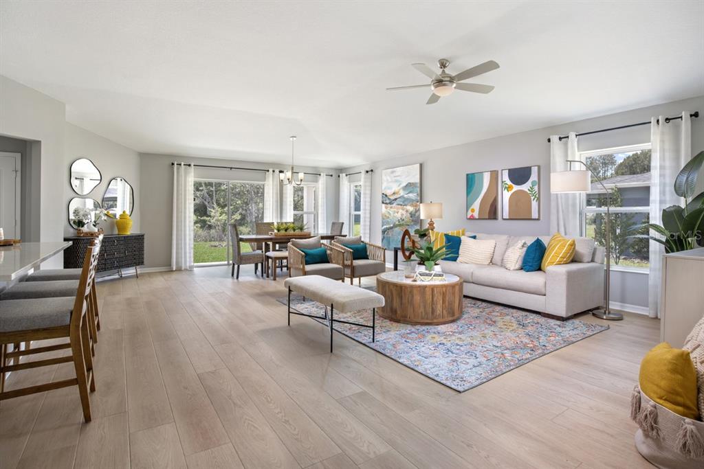 An open-concept living and dining area features light wood flooring, a neutral sofa, and sliding doors — 5531 CREEK HAVEN WAY, LAKELAND, FL