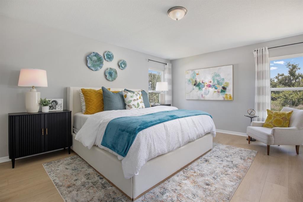 A bedroom features a bed with blue and yellow pillows, a black cabinet, and armchair — 5531 CREEK HAVEN WAY, LAKELAND, FL