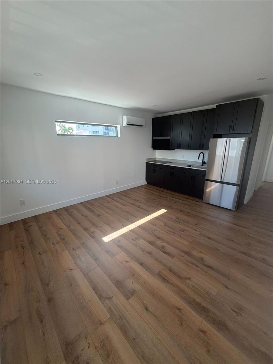A modern kitchen features dark cabinetry, stainless steel appliances, and light wood-look flooring — 7801 Byron Ave # 3, Miami Beach FL 33141, MIAMI BEACH, FL