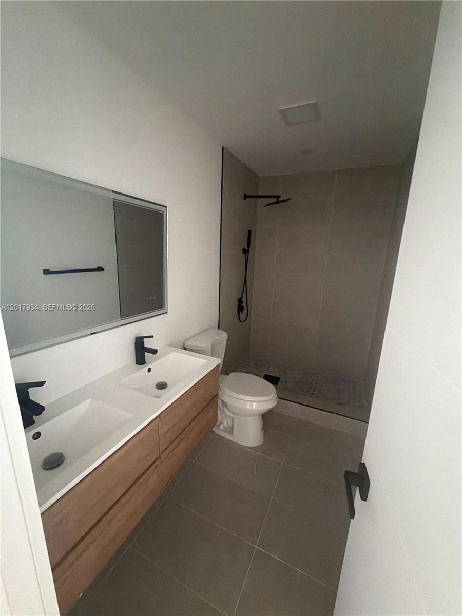 A modern bathroom features a double vanity, a walk-in shower, and a toilet — 7801 Byron Ave # 3, Miami Beach FL 33141, MIAMI BEACH, FL