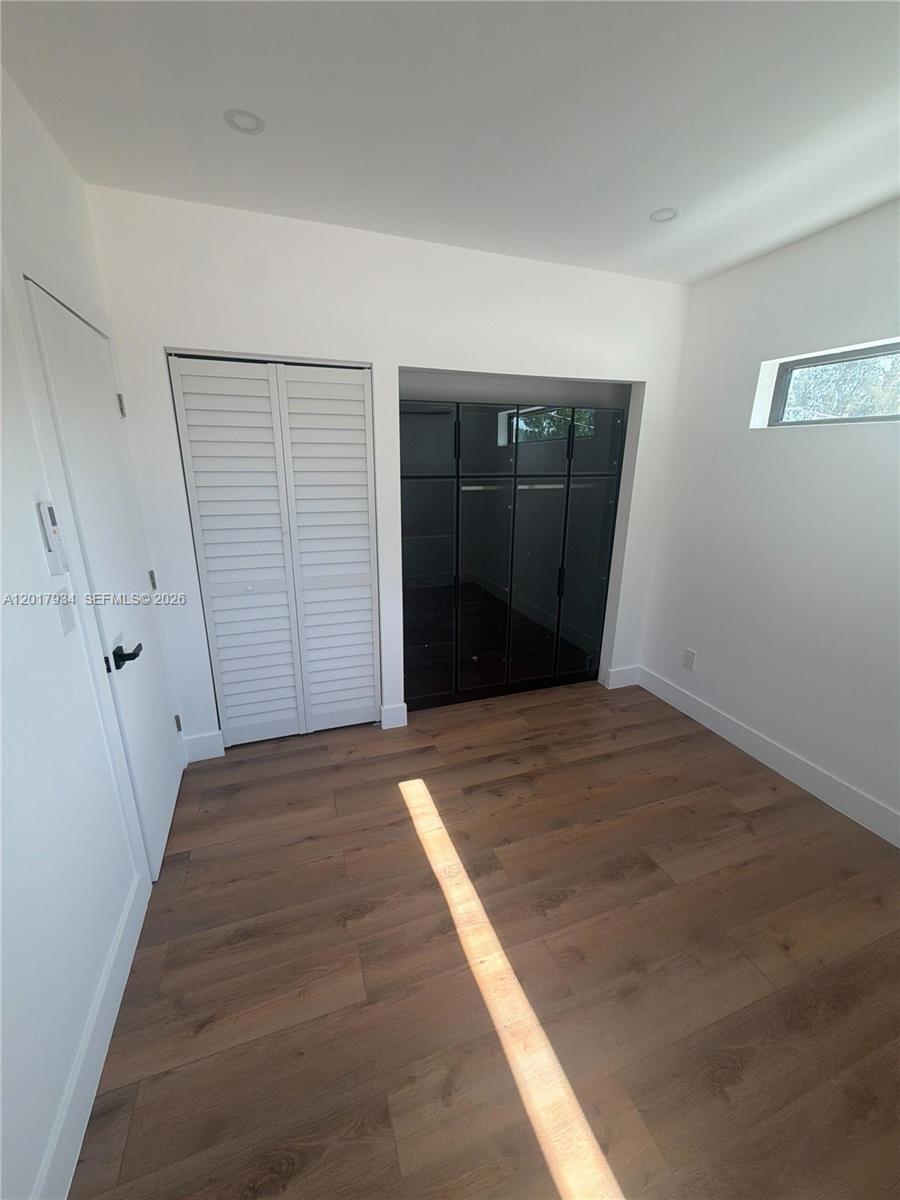 A room features light wood-look flooring, white walls, a louvered closet door, and dark cabinetry — 7801 Byron Ave # 3, Miami Beach FL 33141, MIAMI BEACH, FL