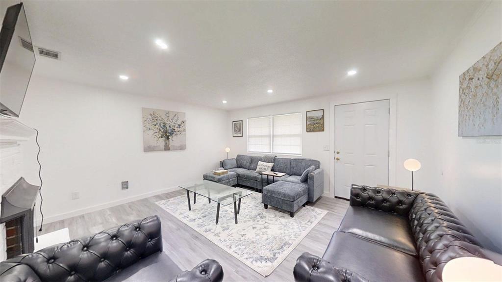 A living room features gray flooring, a sectional sofa, two leather sofas, and a fireplace — 1335 NE 10TH STREET, OCALA, FL