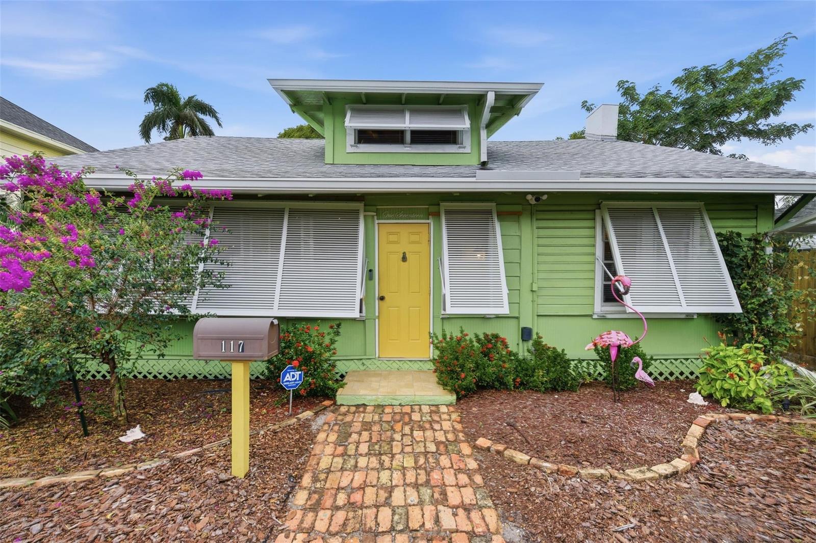 A lime green bungalow with a yellow front door, white shutters, and a brick walkway — 117 S Palmway, FL 33460, FL