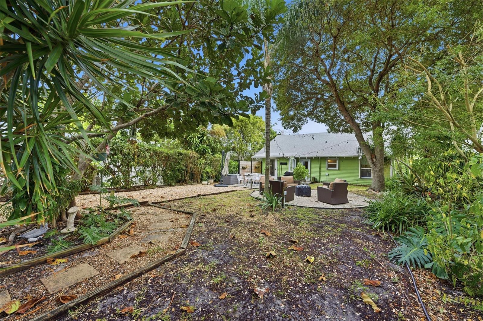 A backyard features a lime green house, a gravel patio with seating, and mature trees — 117 S Palmway, FL 33460, FL