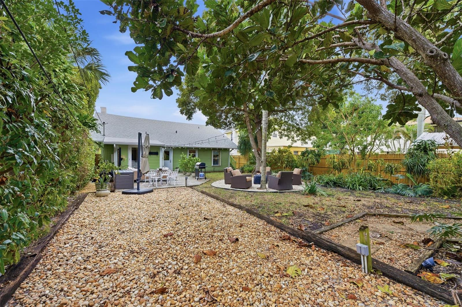 A backyard features a gravel area, a wooden deck, and a circular patio with seating — 117 S Palmway, FL 33460, FL