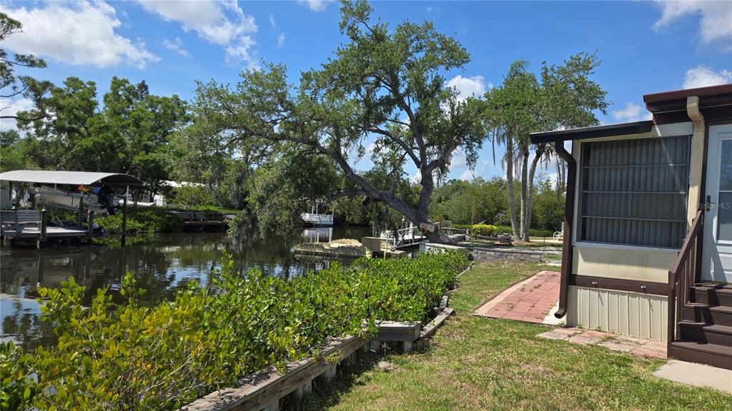 A view of a canal with a boat lift, large trees, and a mobile home exterior — 3333 26TH AVENUE E UNIT 1291, BRADENTON, FL