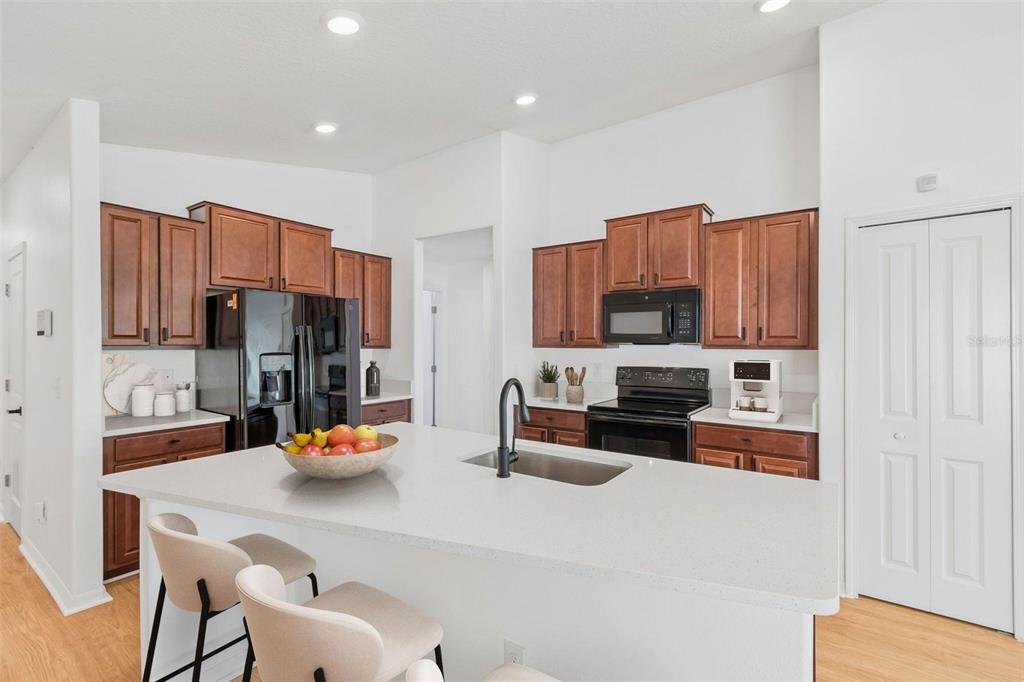 A kitchen with wooden cabinets, a white island, black appliances, and light-colored flooring — 7227 SALT RIVER, SUN CITY CENTER, FL