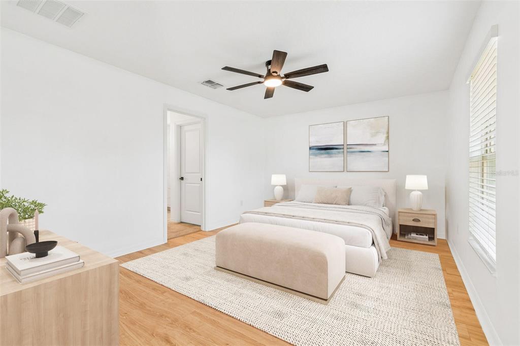 A bright bedroom features a bed, a bench, a ceiling fan, and light wood flooring — 7227 SALT RIVER, SUN CITY CENTER, FL