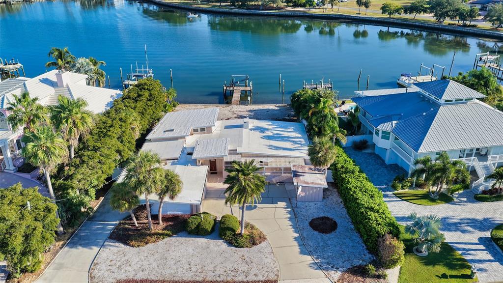 An aerial view shows a waterfront house with a flat roof, palm trees, and dock — 355 S SHORE DRIVE, SARASOTA, FL