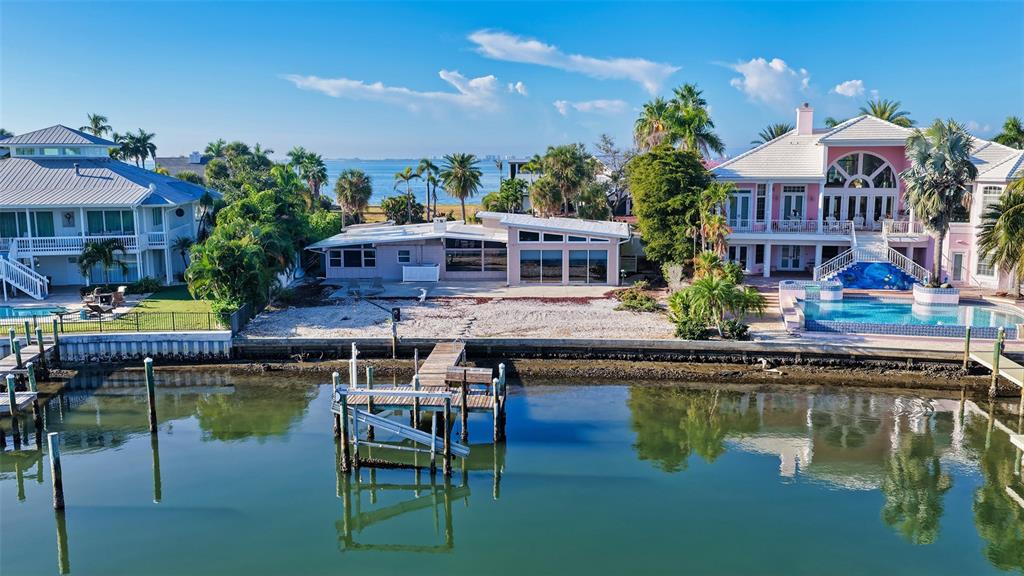 An aerial view shows three waterfront houses with a private dock and a swimming pool — 355 S SHORE DRIVE, SARASOTA, FL
