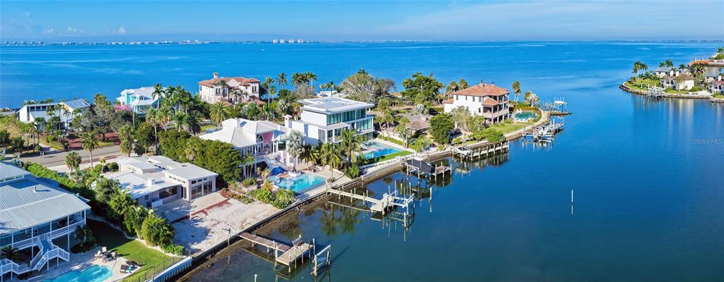 An aerial view shows several waterfront houses with private docks along a calm bay — 355 S SHORE DRIVE, SARASOTA, FL