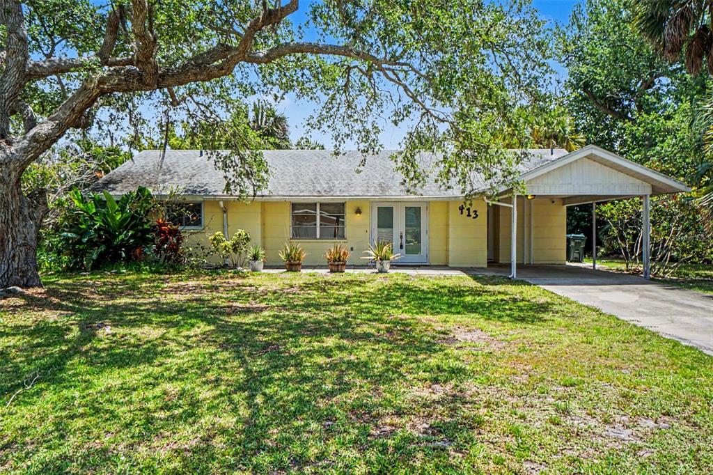 A single-story yellow house with a carport and a large tree in the front yard — 413 PAMETO ROAD, NOKOMIS, FL