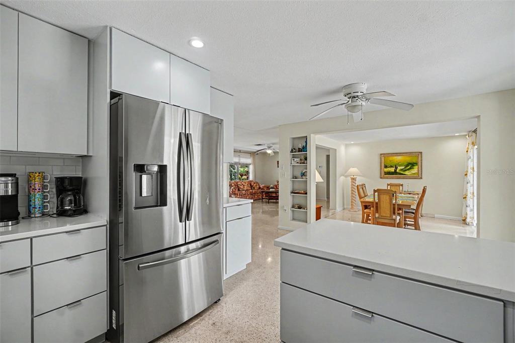 A kitchen with gray cabinets and stainless steel appliances overlooks a dining and living area — 413 PAMETO ROAD, NOKOMIS, FL