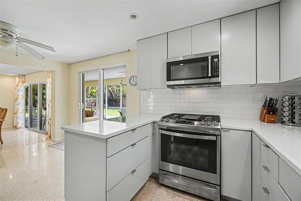 A kitchen features light gray cabinets, white countertops, stainless steel appliances, and a subway tile backsplash — 413 PAMETO ROAD, NOKOMIS, FL