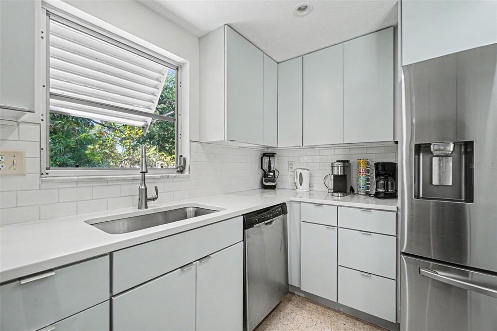 A kitchen features light gray cabinets, stainless steel appliances, white countertops, and a subway tile backsplash — 413 PAMETO ROAD, NOKOMIS, FL