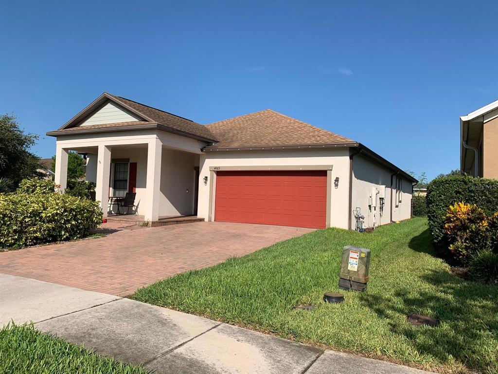 A single-story house with a red garage door, a brick driveway, and a covered porch — 4063 WELLING TERRACE, LAND O LAKES, FL
