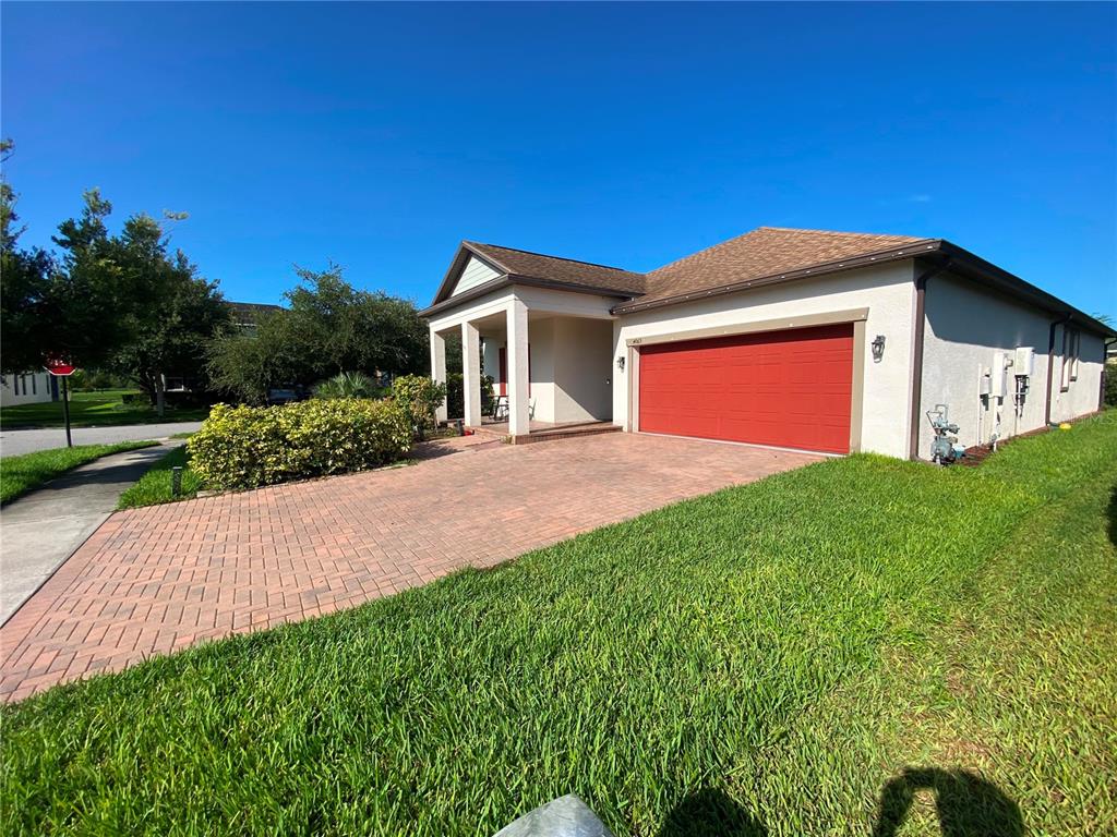 A single-story house with a red garage door and a paved driveway under a blue sky — 4063 WELLING TERRACE, LAND O LAKES, FL