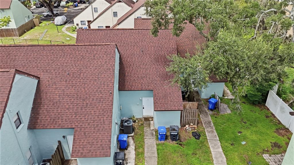 An aerial view of a light blue townhouse with a brown shingled roof and yard — 12414 TOUCHTON DRIVE UNIT 100, TAMPA, FL