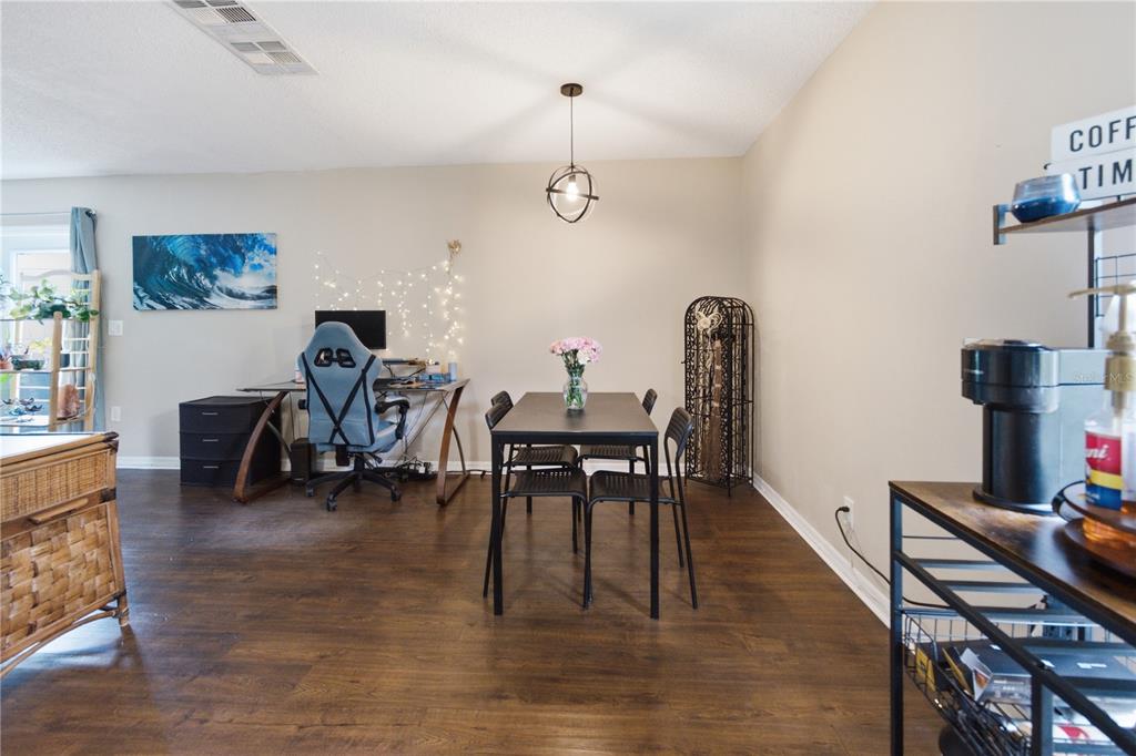 A dining area features a dark table, four chairs, and a nearby computer desk setup — 12414 TOUCHTON DRIVE UNIT 100, TAMPA, FL
