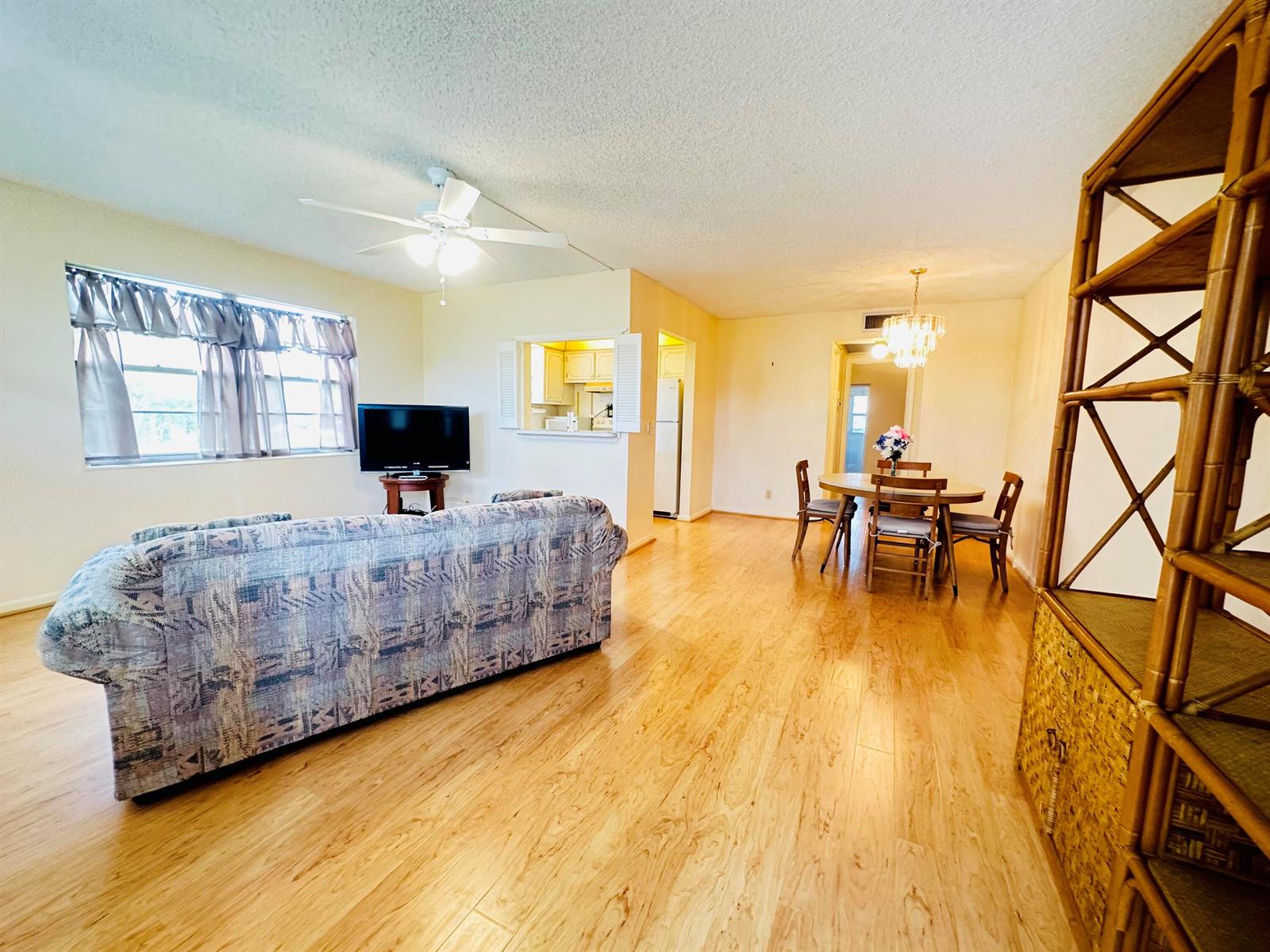 A living and dining area with light wood flooring, a ceiling fan, and a pass-through window — 269 Farnham L, Deerfield Beach FL 33442, DEERFIELD BEACH, FL