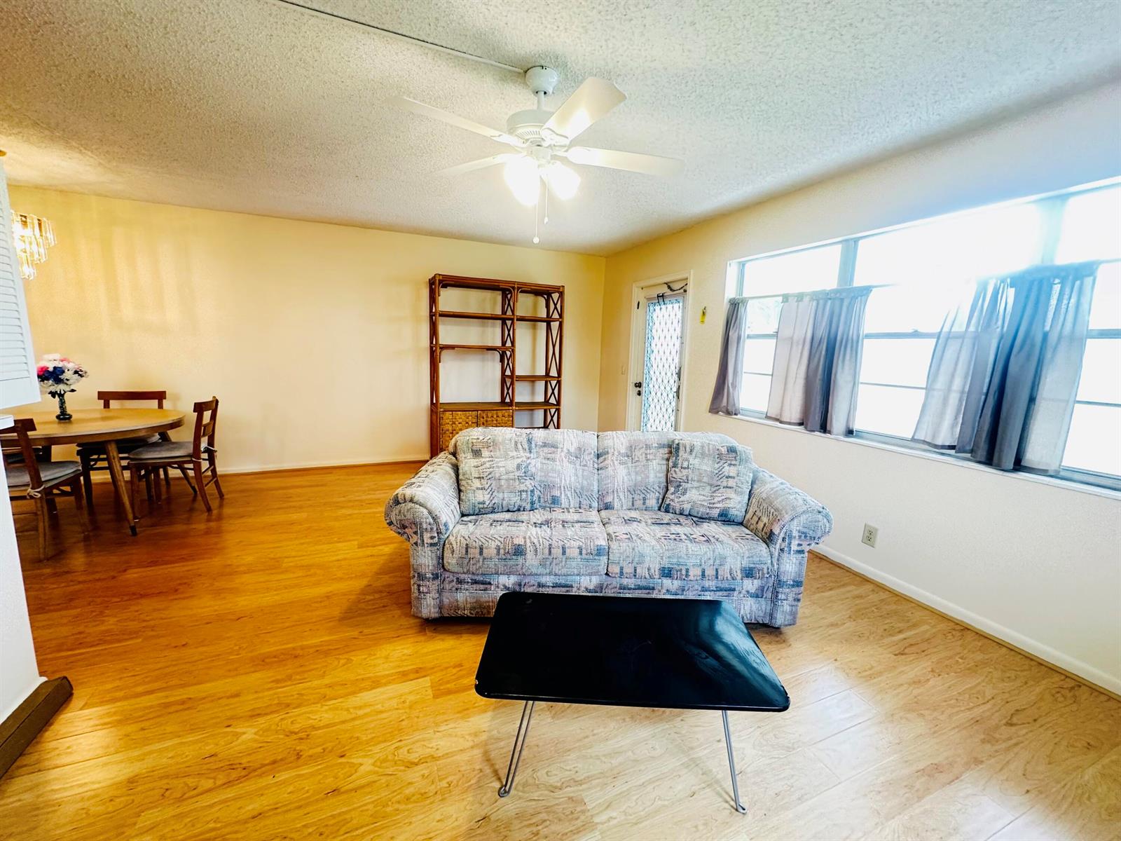 A living room with wood flooring, a patterned sofa, a coffee table, and a dining area — 269 Farnham L, Deerfield Beach FL 33442, DEERFIELD BEACH, FL
