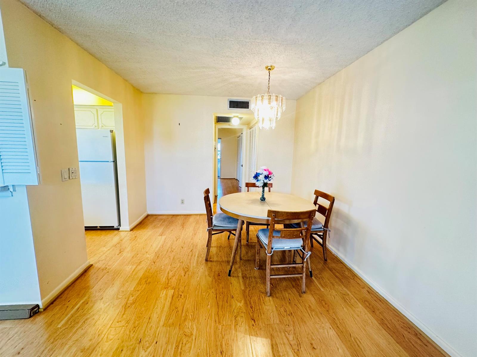 A dining area with a round wooden table, chairs, and a crystal chandelier on wood flooring — 269 Farnham L, Deerfield Beach FL 33442, DEERFIELD BEACH, FL