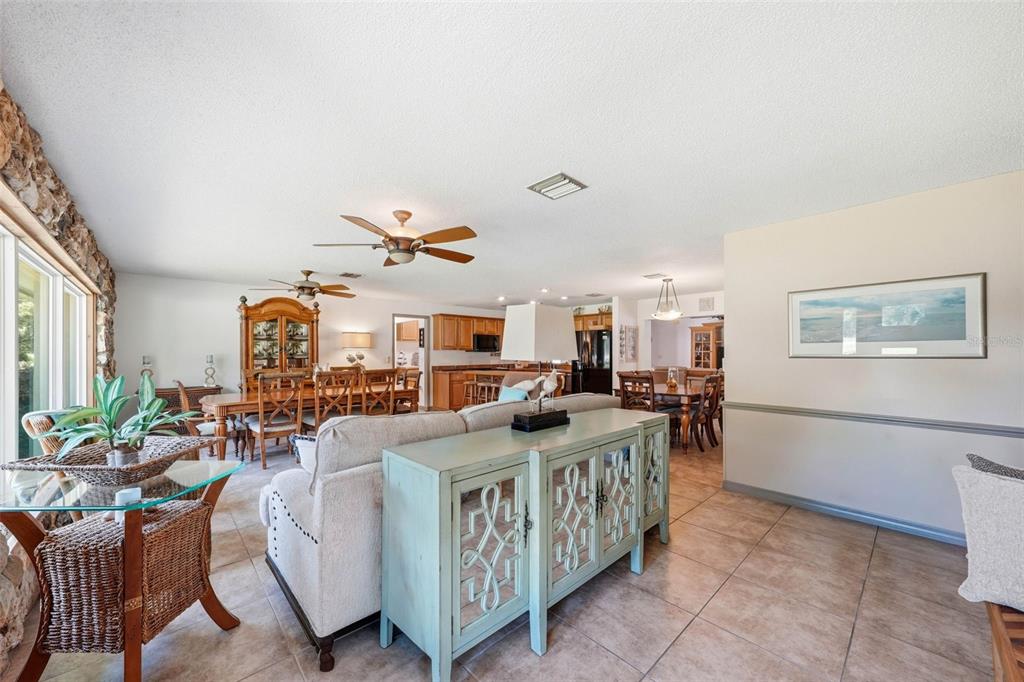 An open-concept living and dining area features tile flooring, a stone wall, and wooden cabinetry — 37237 GRAYS AIRPORT ROAD, LADY LAKE, FL