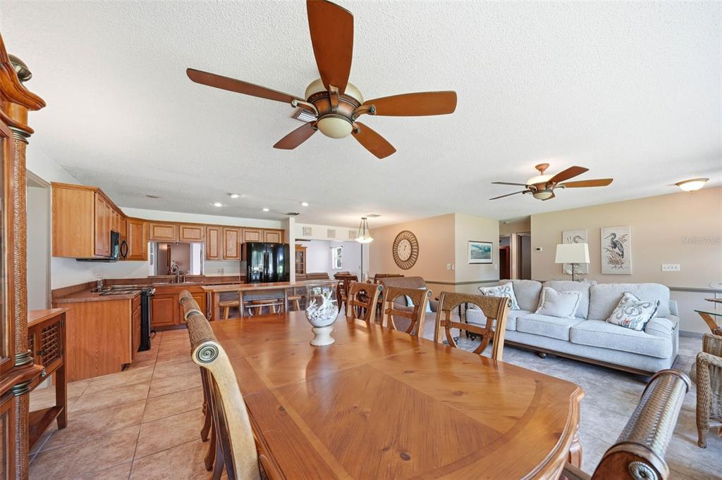An open-concept dining room, kitchen, and living area with wood furniture and tile flooring — 37237 GRAYS AIRPORT ROAD, LADY LAKE, FL