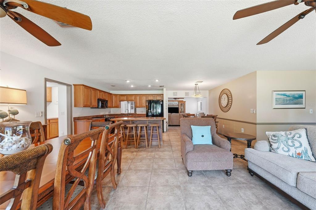 A living room and kitchen area with tile flooring, wooden cabinets, and ceiling fans — 37237 GRAYS AIRPORT ROAD, LADY LAKE, FL