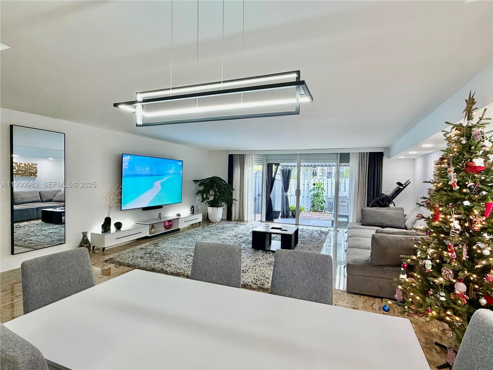 A living room features a large television, a modern light fixture, and a Christmas tree — 934 NE 27th Ave, Hallandale Beach FL 33009, HALLANDALE BEACH, FL