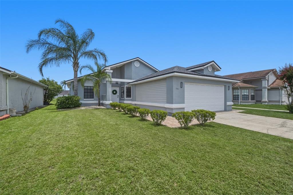 A single-story suburban house with a gray exterior, a two-car garage, and a palm tree — 1009 WHALEBONE BAY DRIVE, KISSIMMEE, FL