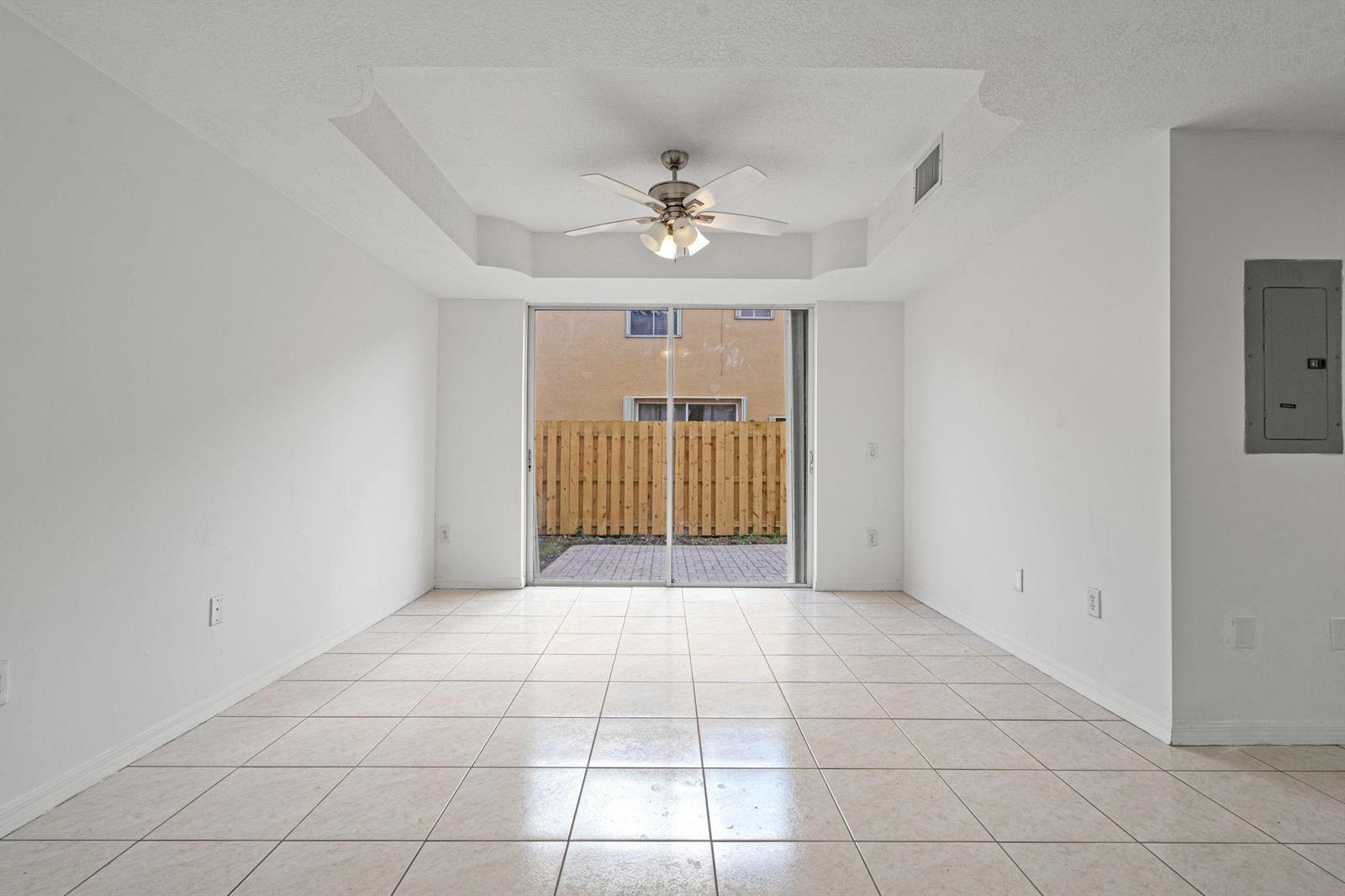 An empty room with white walls, tile flooring, a tray ceiling, and sliding glass doors — 8520 NW 139th Terrace # 1602, Miami Lakes FL 33016, MIAMI LAKES, FL