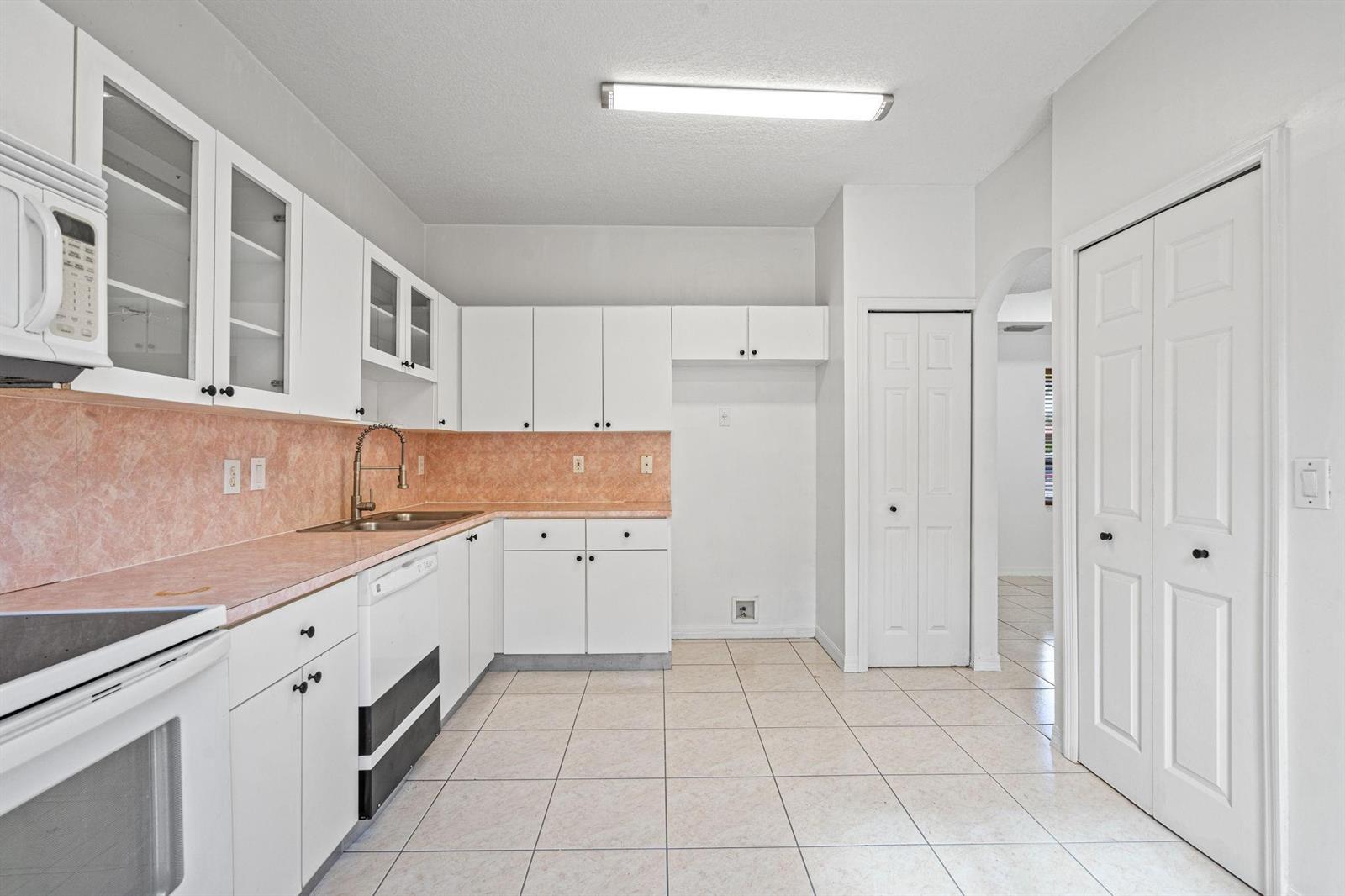 A kitchen with white cabinets, pink countertops, tiled floors, and a white appliance suite — 8520 NW 139th Terrace # 1602, Miami Lakes FL 33016, MIAMI LAKES, FL