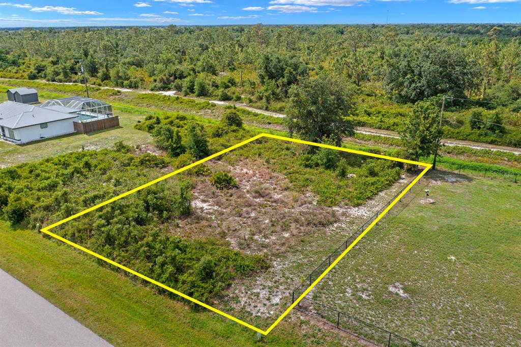 An aerial view shows a vacant, rectangular residential lot outlined in yellow near a house — 29331 LILLIS STREET, PUNTA GORDA, FL