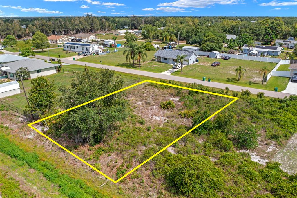 An aerial view shows a vacant, rectangular residential lot outlined in yellow near a road — 29331 LILLIS STREET, PUNTA GORDA, FL