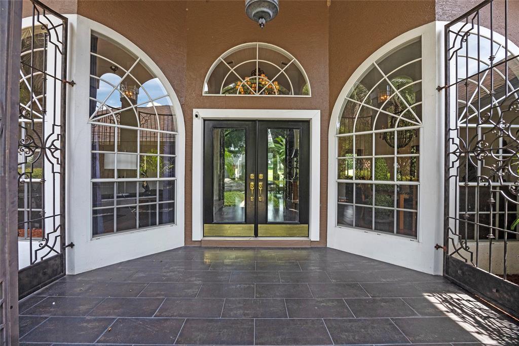 A front entryway features double glass doors flanked by arched windows and decorative iron gates — 6631 CRENSHAW DRIVE, ORLANDO, FL