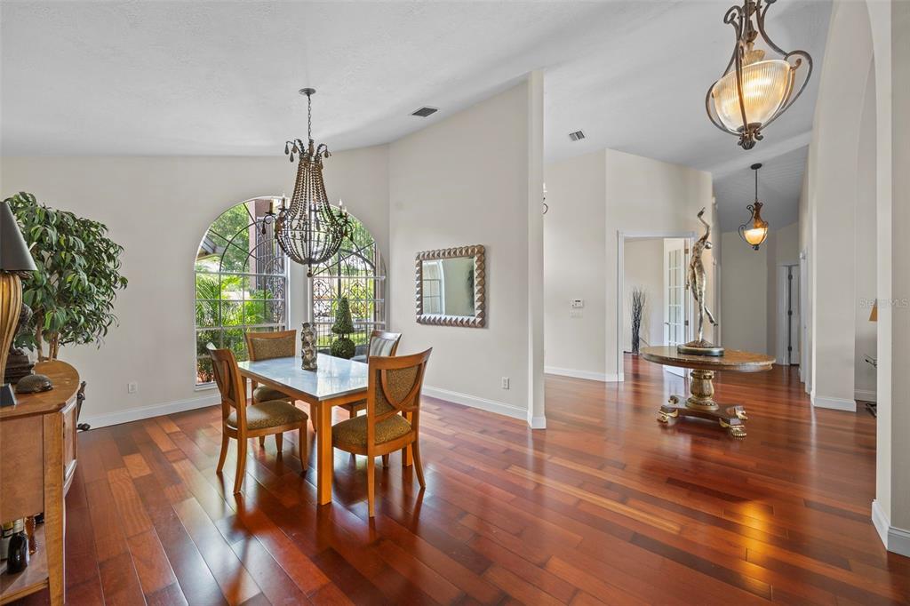 A dining room features hardwood floors, a large arched window, and a decorative chandelier — 6631 CRENSHAW DRIVE, ORLANDO, FL