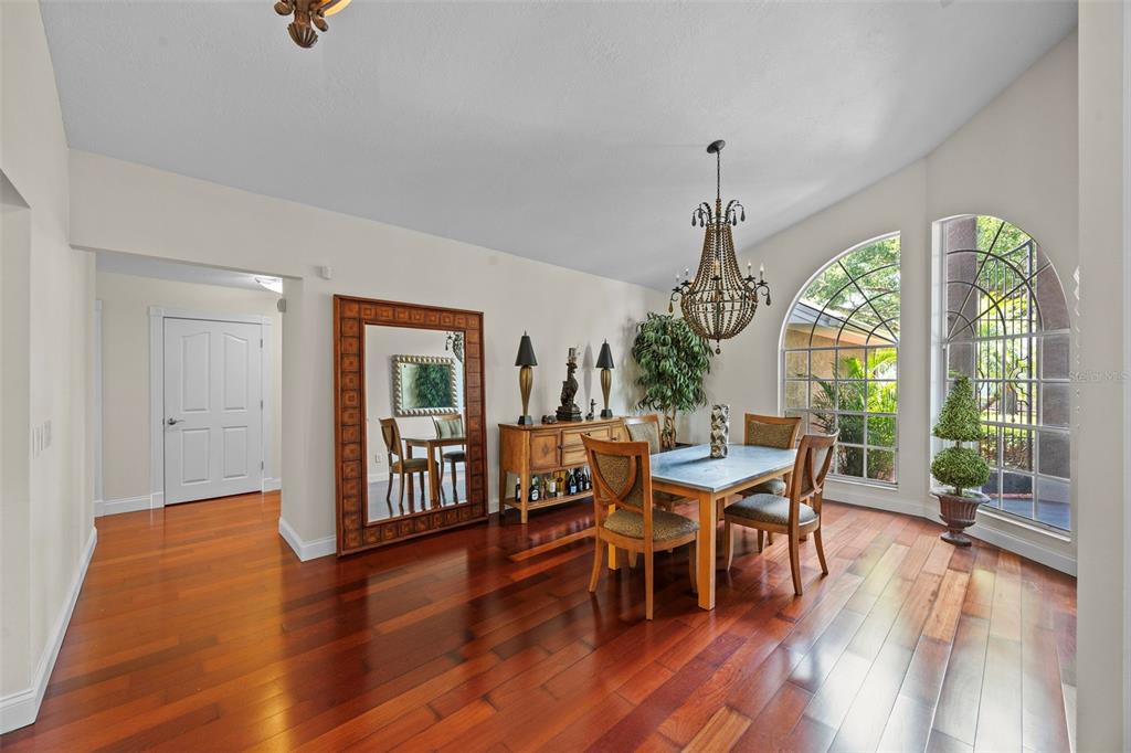 A dining room with hardwood floors, a large mirror, and a chandelier near arched windows — 6631 CRENSHAW DRIVE, ORLANDO, FL