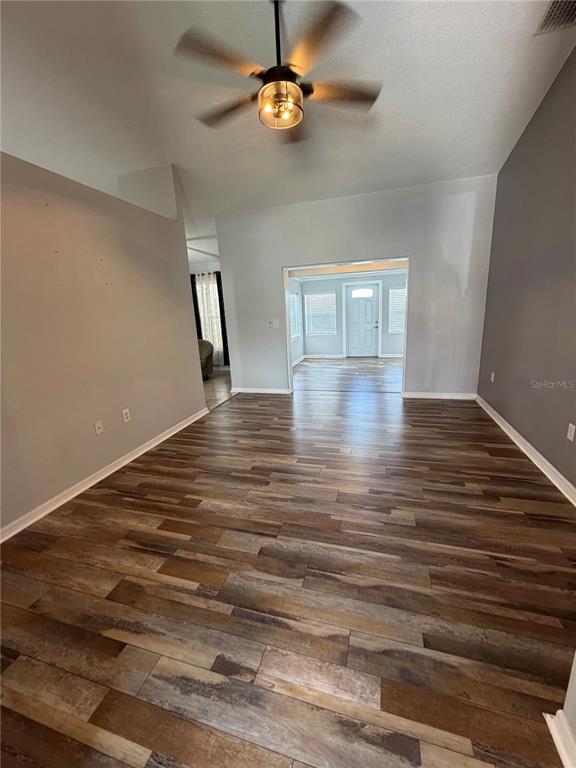 A living area with wood-look flooring, a ceiling fan, and an opening to another room — 8871 PEBBLEBROOKE DRIVE, LAKELAND, FL