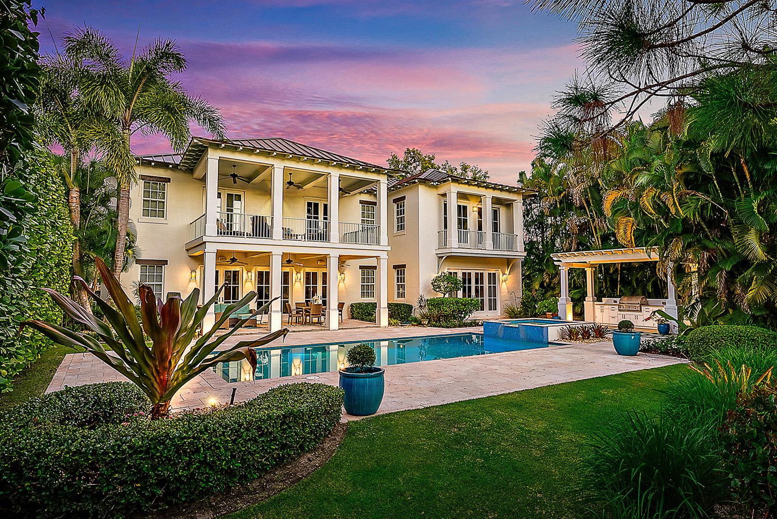 A two-story house with a pool, covered patio, and outdoor kitchen at sunset — 18706 SE St Augustine Way, Jupiter FL 33458, JUPITER, FL