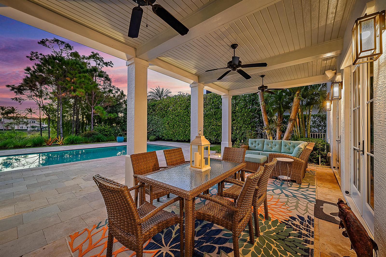 A covered patio features wicker dining and lounge furniture, ceiling fans, and a swimming pool — 18706 SE St Augustine Way, Jupiter FL 33458, JUPITER, FL