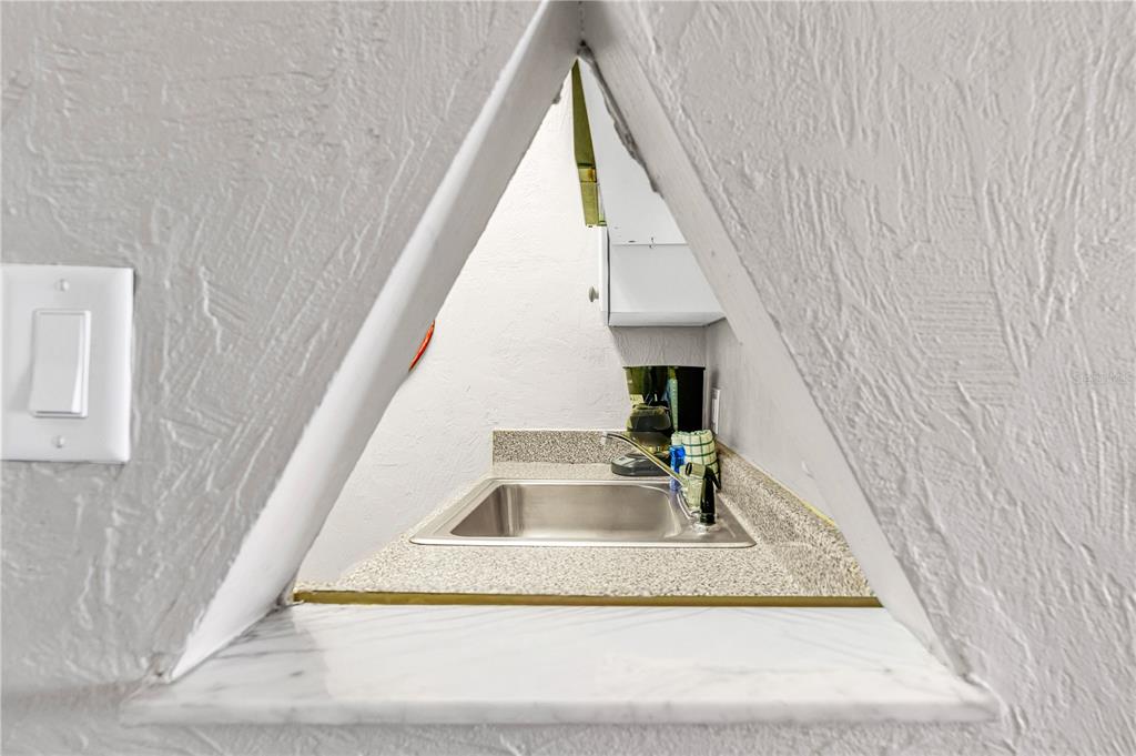 A triangular pass-through window looks into a small kitchen area with a stainless sink — 313 S ATLANTIC AVENUE UNIT 5310, DAYTONA BEACH, FL