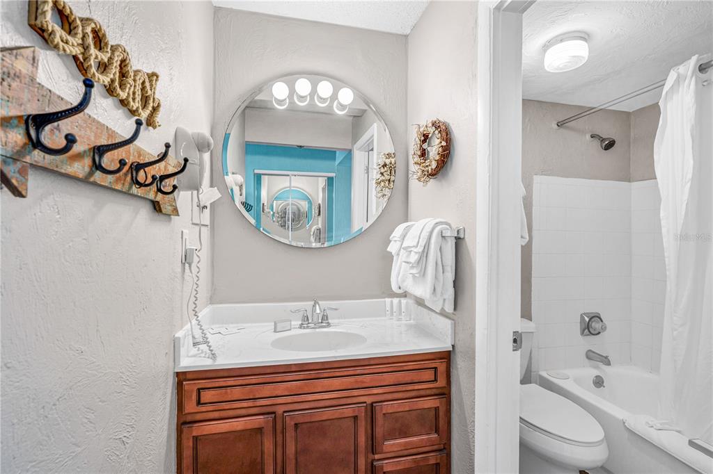 A bathroom features a wooden vanity, a round mirror, and a shower-tub combination — 313 S ATLANTIC AVENUE UNIT 5310, DAYTONA BEACH, FL