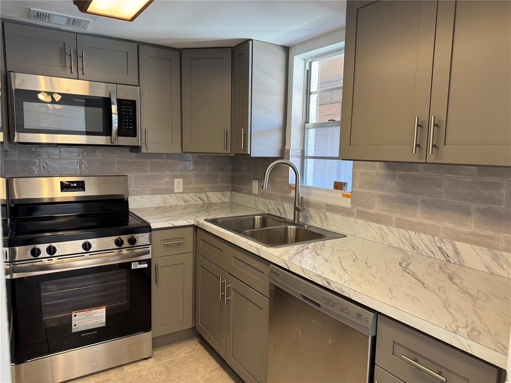 A kitchen features gray cabinets, stainless steel appliances, and white marble-patterned countertops — 5154 TURQUOISE LANE UNIT 102, NEW PORT RICHEY, FL