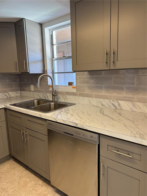 A kitchen features gray cabinets, marble-patterned countertops, a stainless steel dishwasher, and a tiled backsplash — 5154 TURQUOISE LANE UNIT 102, NEW PORT RICHEY, FL